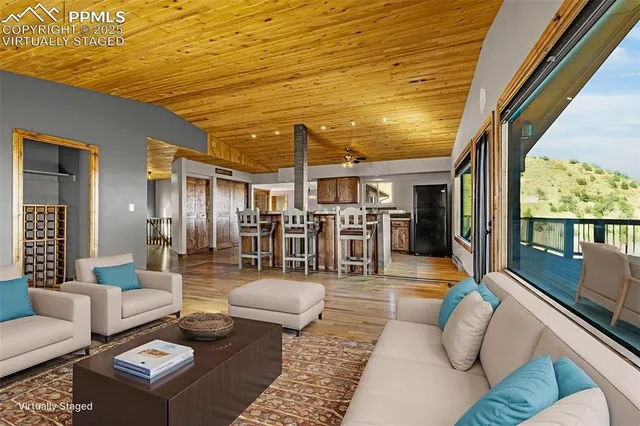a view of a livingroom with wooden floor kitchen space and windows