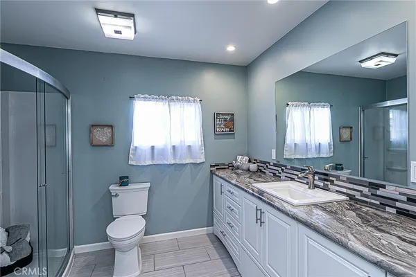 a bathroom with a granite countertop sink toilet and a mirror