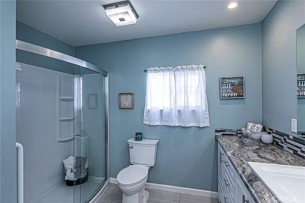 a bathroom with a granite countertop toilet a sink and a mirror