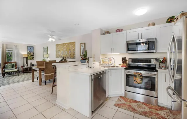 a kitchen with stainless steel appliances granite countertop a stove top oven a sink a dining table and chairs