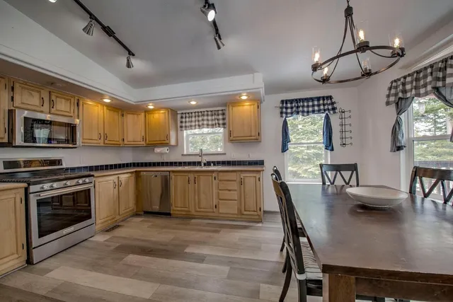 a kitchen with granite countertop a stove a sink dishwasher a dining table and chairs with wooden floor
