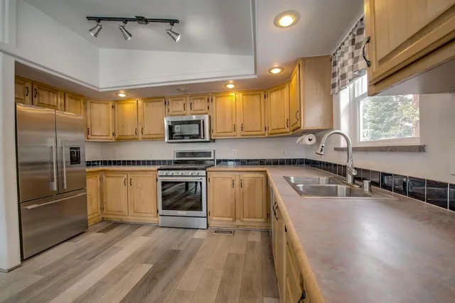 a kitchen with kitchen island granite countertop a sink cabinets and stainless steel appliances