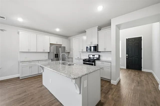 a kitchen with stainless steel appliances granite countertop a sink dishwasher stove top oven and refrigerator