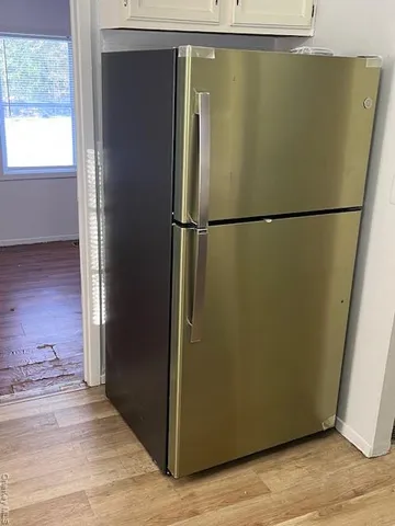a view of a refrigerator in kitchen and an empty room