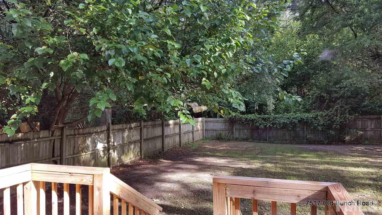 7517 Old Bunch Road Zebulon, NC 27597 - Photo 18 of 25 a view of a backyard with large trees and wooden fence