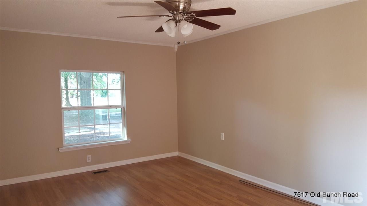 7517 Old Bunch Road Zebulon, NC 27597 - Photo 7 of 25 an empty room with wooden floor fan and windows
