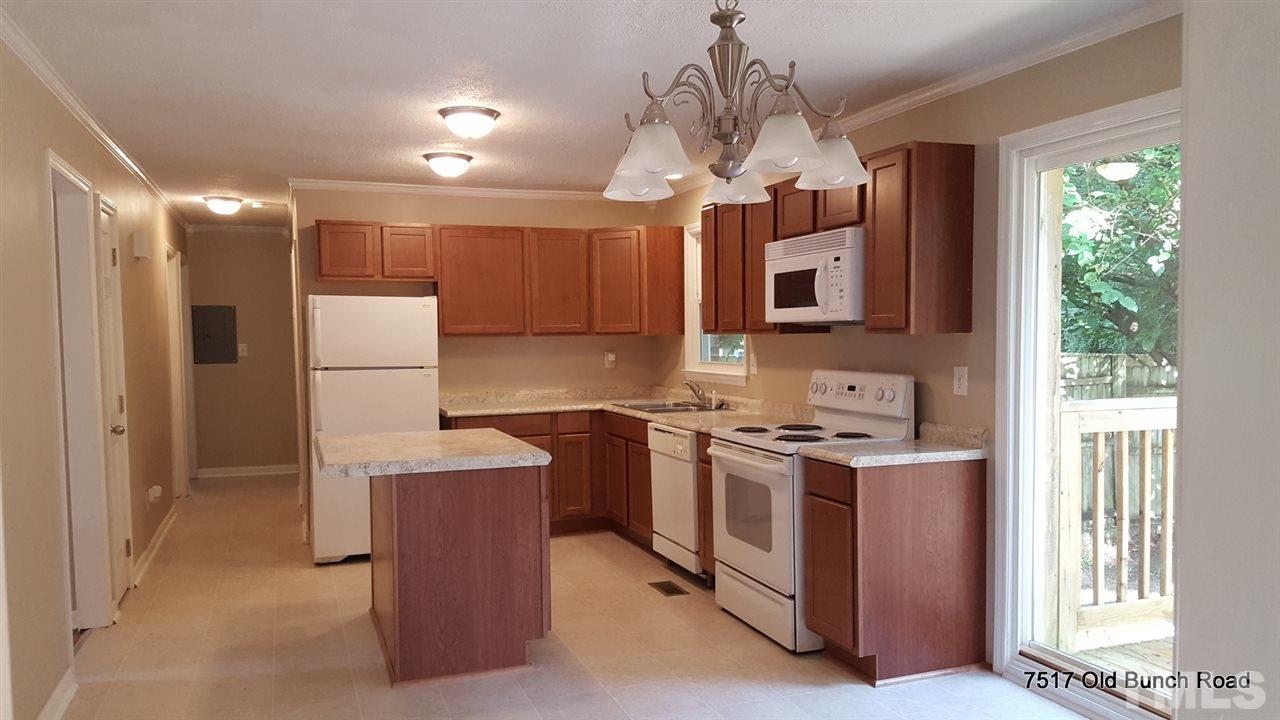 7517 Old Bunch Road Zebulon, NC 27597 - Photo 8 of 25 a kitchen with stainless steel appliances granite countertop a stove top oven a refrigerator a sink and a dining table with wooden floor