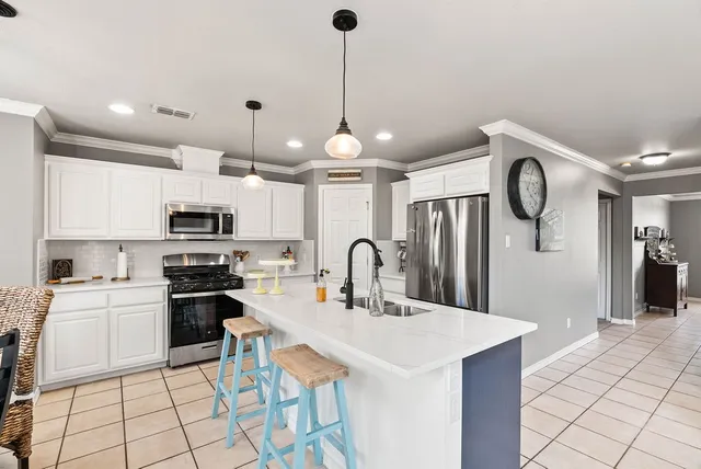 a kitchen with stainless steel appliances a stove a sink island and a refrigerator