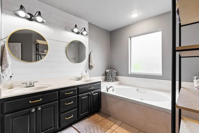 a bathroom with a double vanity sink mirror and bathtub