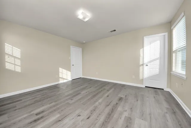 a view of an empty room with wooden floor and window