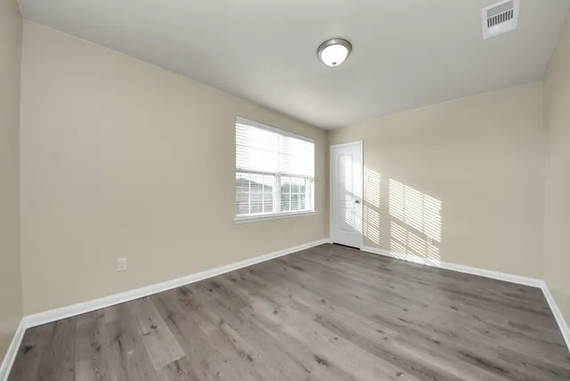 an empty room with wooden floor and windows