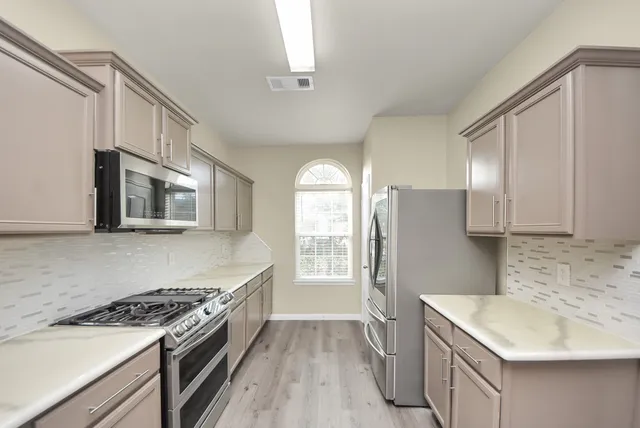 an empty room with wooden floor cabinet and windows