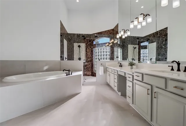 a bathroom with a tub a sink double vanity and a mirror