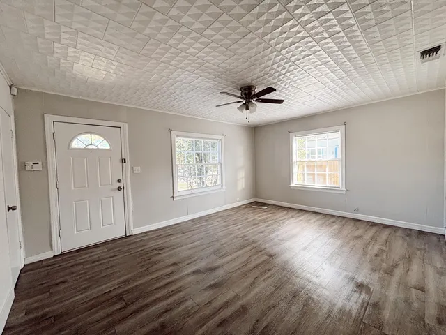 a view of an empty room with a window and wooden floor