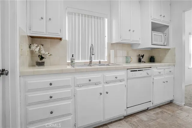 a kitchen with granite countertop white cabinets and white appliances