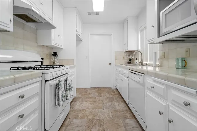 a kitchen with granite countertop cabinets a sink a stove and a refrigerator
