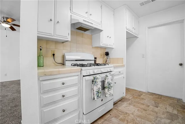 a kitchen with white cabinets and appliances