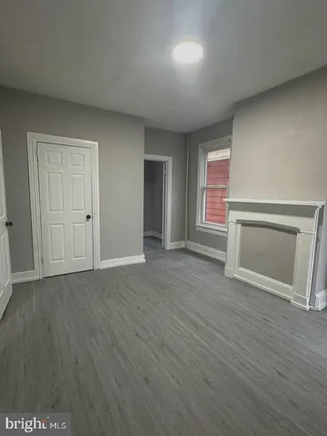 an empty room with wooden floor fireplace and windows