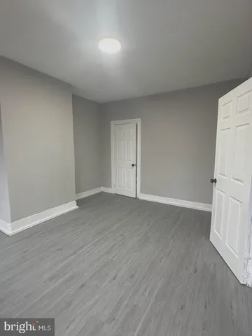 a view of an empty room with wooden floor and a refrigerator