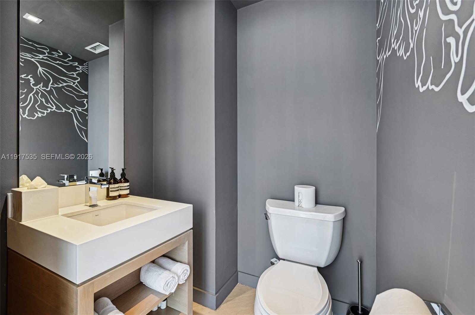 2201 Collins Avenue, Unit 401 Miami Beach, FL 33139 - Photo 13 of 20 a bathroom with a toilet a sink and a mirror