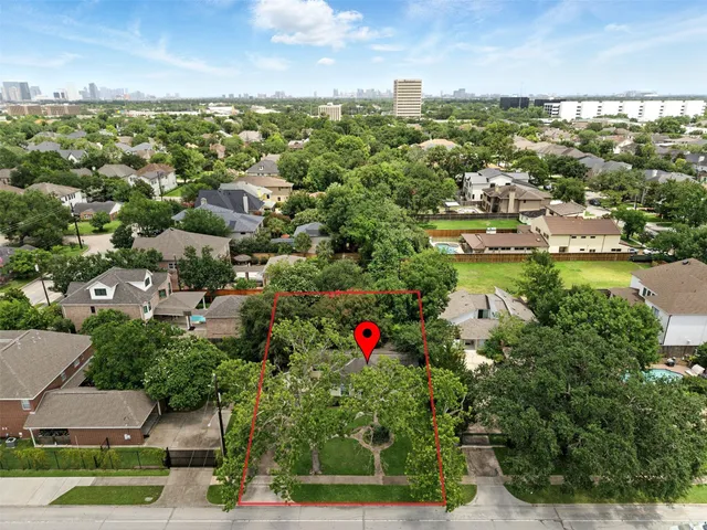 an aerial view of residential houses with outdoor space and trees