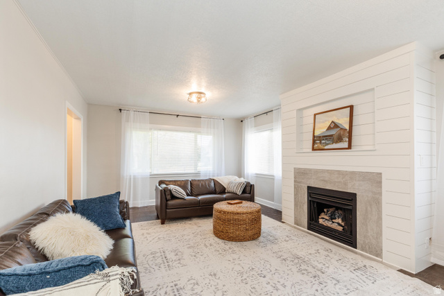 227 West 200 North Logan, UT 84321 - Photo 12 of 44 Living room featuring a shiplap-accented fireplace with a light gray surround, dark wood-finish flooring, and multiple windows