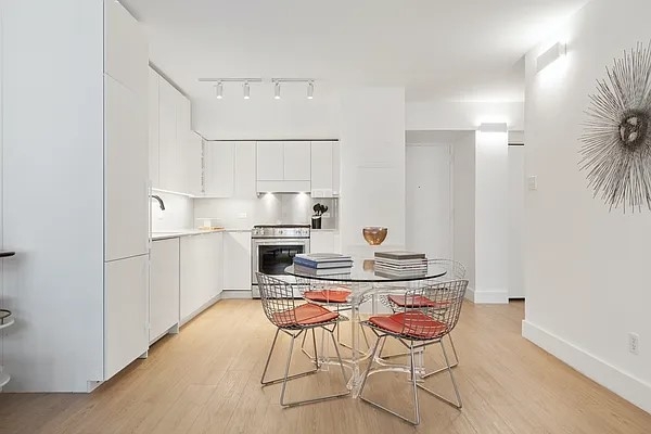 160 West 24th Street, Unit 14K Manhattan, NY 10011 - Photo 6 of 11 a kitchen with stainless steel appliances kitchen island granite countertop a dining table chairs and a refrigerator