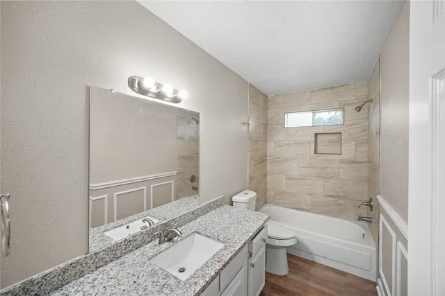 a bathroom with a granite countertop bathtub shower sink and toilet