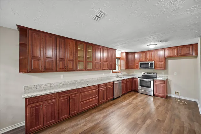a kitchen with stainless steel appliances granite countertop wooden cabinets a stove top oven a sink and dishwasher