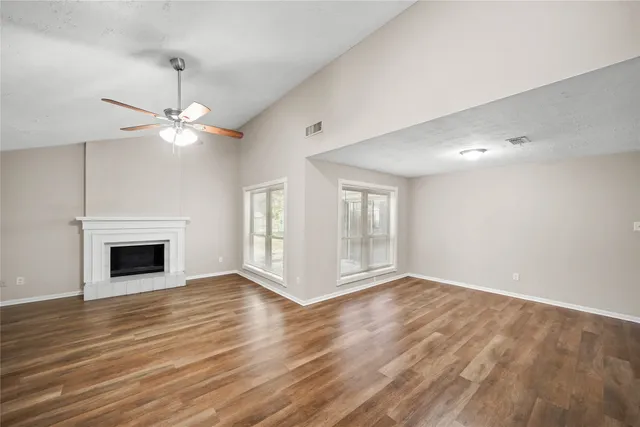 a view of an empty room with wooden floor fireplace and a window
