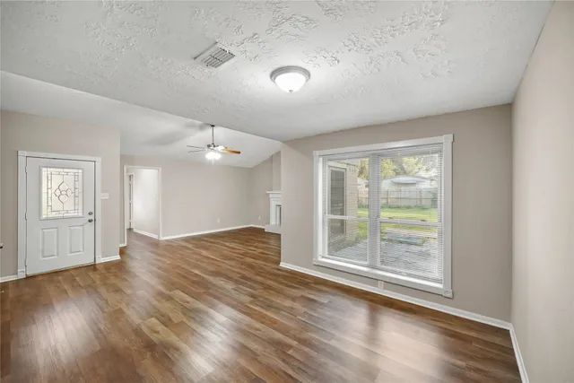 an empty room with wooden floor cabinet and windows