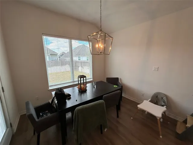 a kitchen with stainless steel appliances granite countertop a refrigerator a stove a sink dishwasher a dining table and chairs with wooden floor