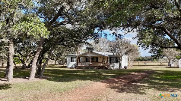 a front view of a house with a large tree