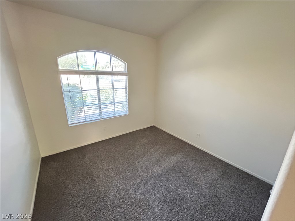1840 Montvale Las Vegas, NV 89134 - Photo 12 of 31 An arched window frames outdoor greenery, casting soft light onto the inviting carpeted floor.