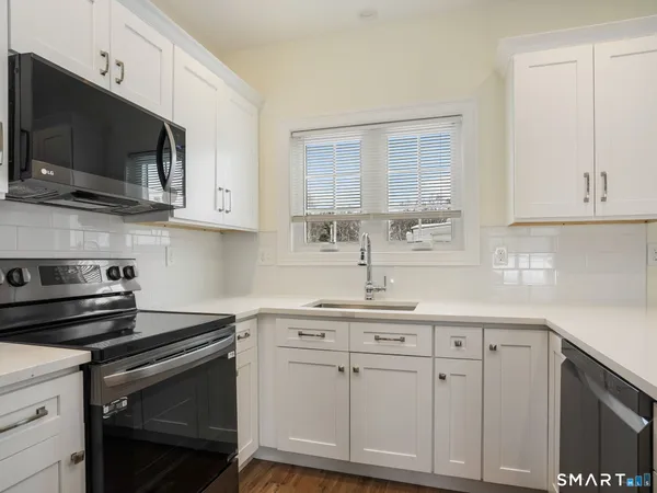 a kitchen with stainless steel appliances granite countertop a sink a stove a microwave and cabinets