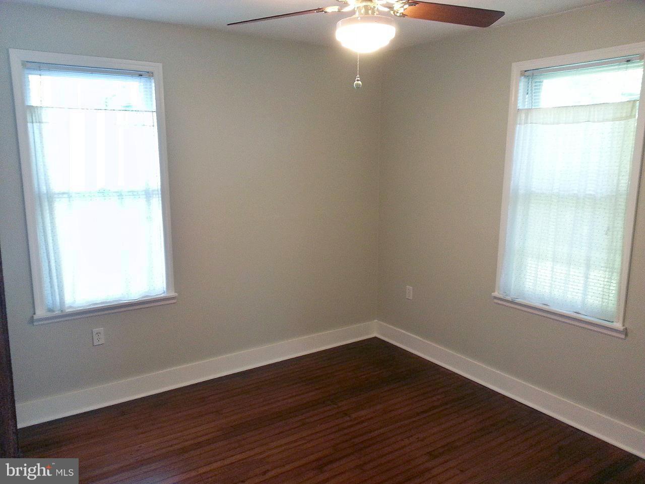 1108 Overbrook Road Baltimore, MD 21239 - Photo 10 of 20 an empty room with wooden floor and windows