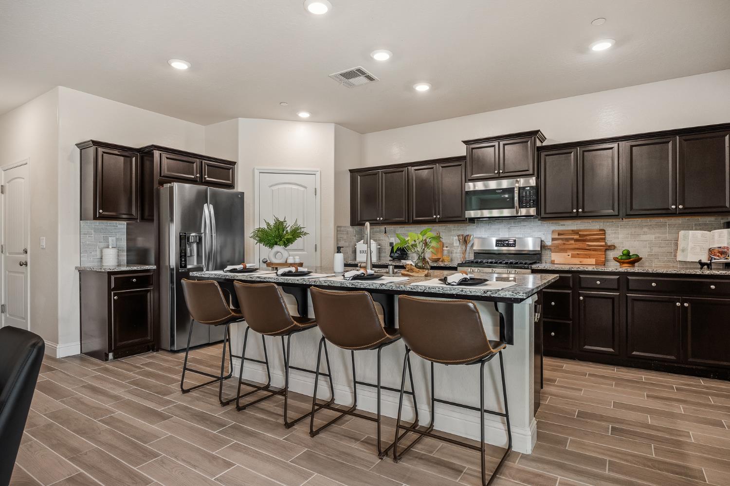 315 Timberline Way Madera, CA 93636 - Photo 29 of 75 a kitchen with stainless steel appliances kitchen island granite countertop a refrigerator a stove a sink a dining table and chairs with wooden floor