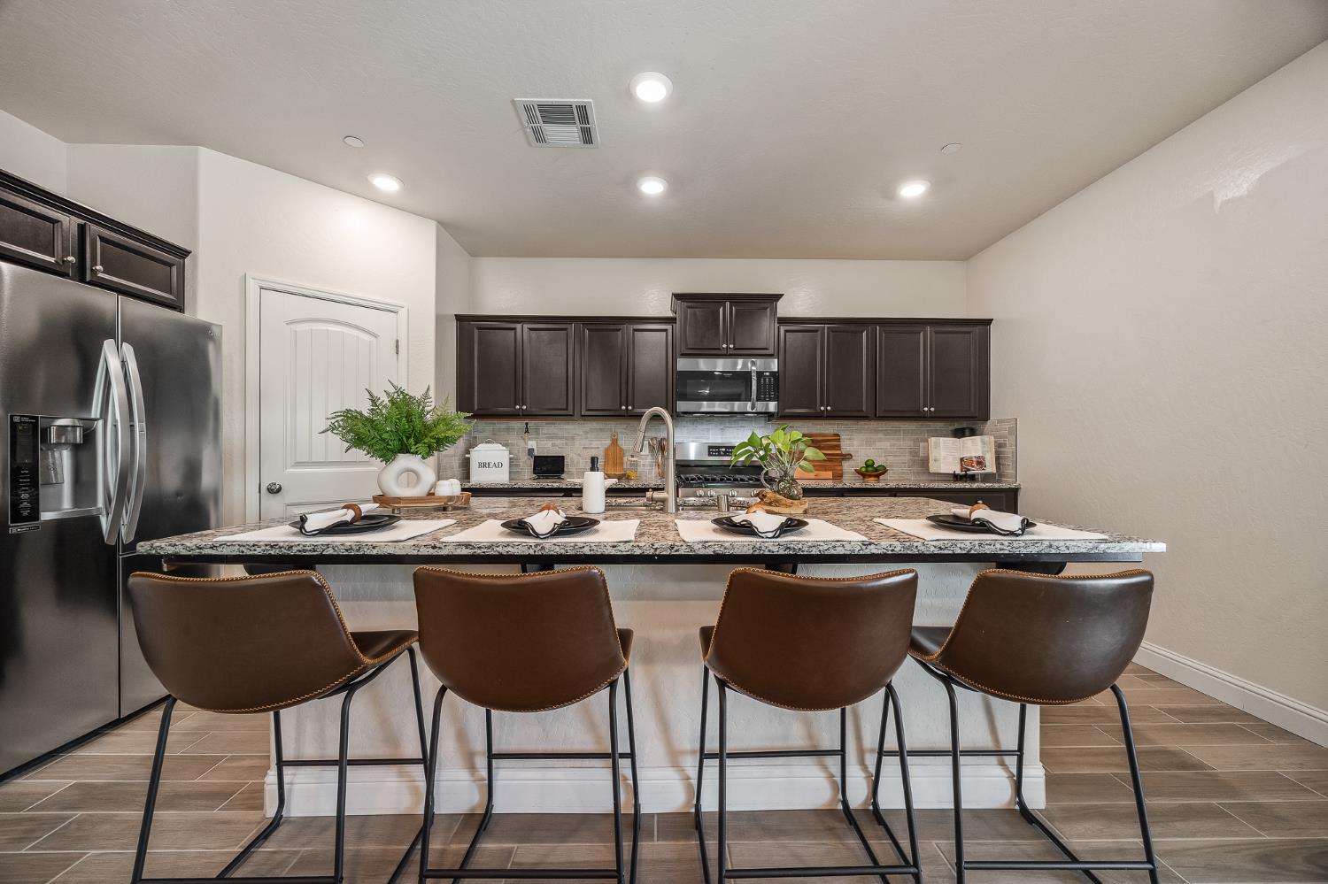 315 Timberline Way Madera, CA 93636 - Photo 31 of 75 a kitchen with stainless steel appliances granite countertop a sink a stove a refrigerator and chairs