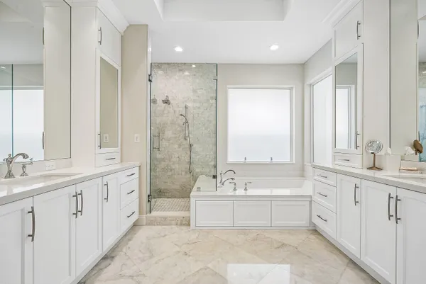 a view of a white house next to a yard with potted plants