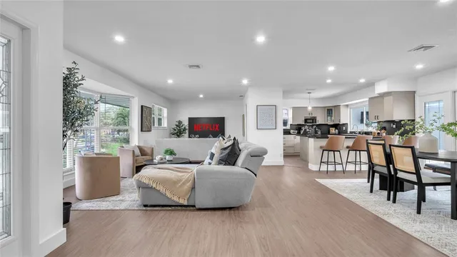 a living room with furniture wooden floor and a kitchen view