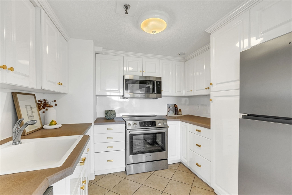 1731 Beacon Street, Unit 1515 Brookline, MA 02445 - Photo 19 of 40 a kitchen with cabinets stainless steel appliances and a counter space