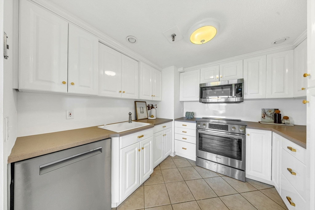 1731 Beacon Street, Unit 1515 Brookline, MA 02445 - Photo 20 of 40 a kitchen with stainless steel appliances granite countertop a sink and dishwasher a stove top oven with white cabinets