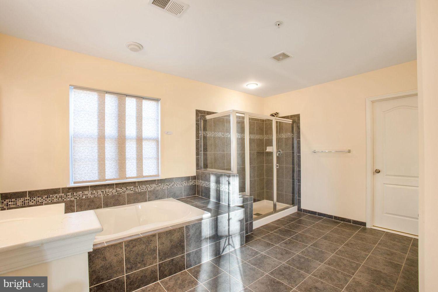 3041 Bel Pre Road Silver Spring, MD 20906 - Photo 19 of 30 a spacious bathroom with a large tub shower and checkered floor