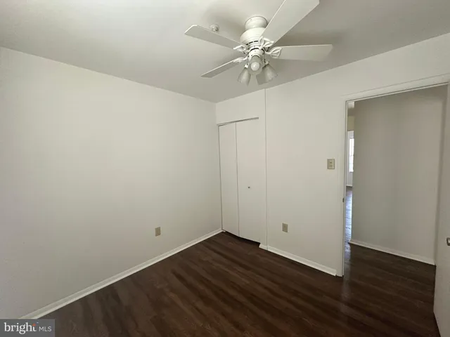 an empty room with wooden floor and fan