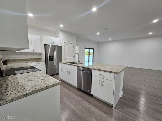 a kitchen with stainless steel appliances granite countertop a sink stove refrigerator and cabinets