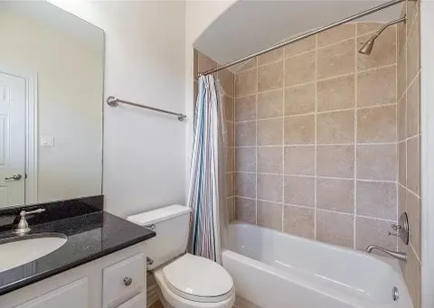 a bathroom with a granite countertop bathtub shower sink vanity and toilet