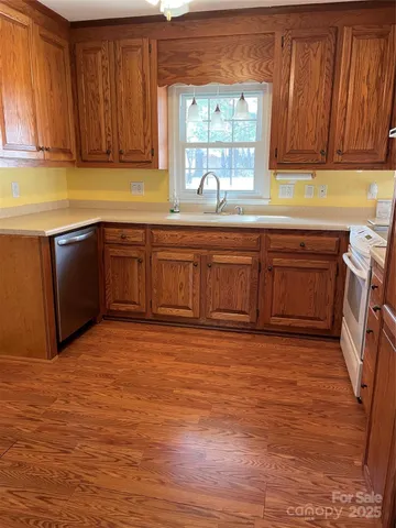 a kitchen with stainless steel appliances granite countertop a sink and cabinets with wooden floor
