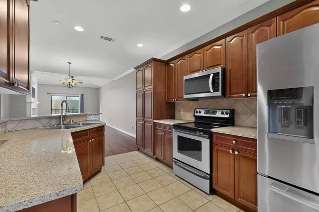 a kitchen with stainless steel appliances granite countertop a refrigerator a stove top oven and sink