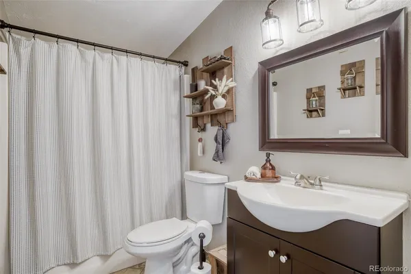 a bathroom with a sink a toilet and shower curtain