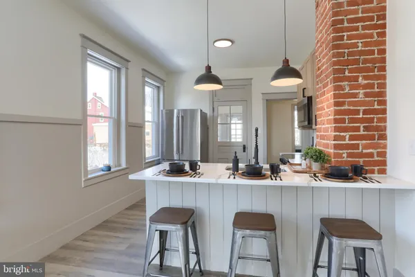 a kitchen with a stove a sink and white cabinets with wooden floor